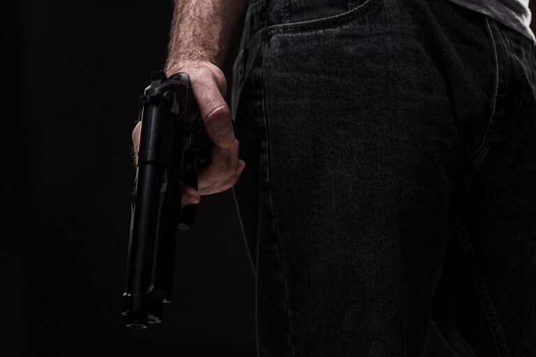Killer with gun on black background at the studio