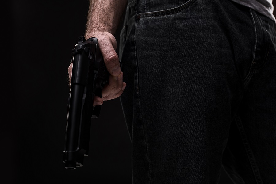 Killer with gun on black background at the studio
